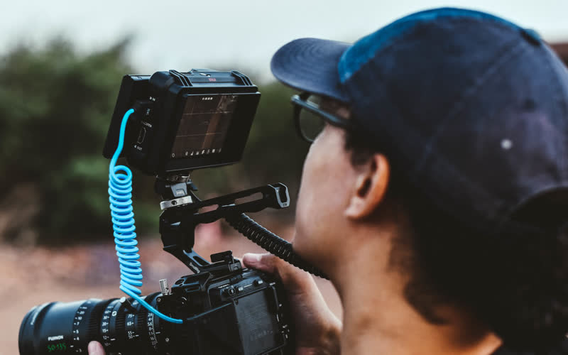 Cadreur au travail derrière une caméra cinéma équipée d'un moniteur de contrôle