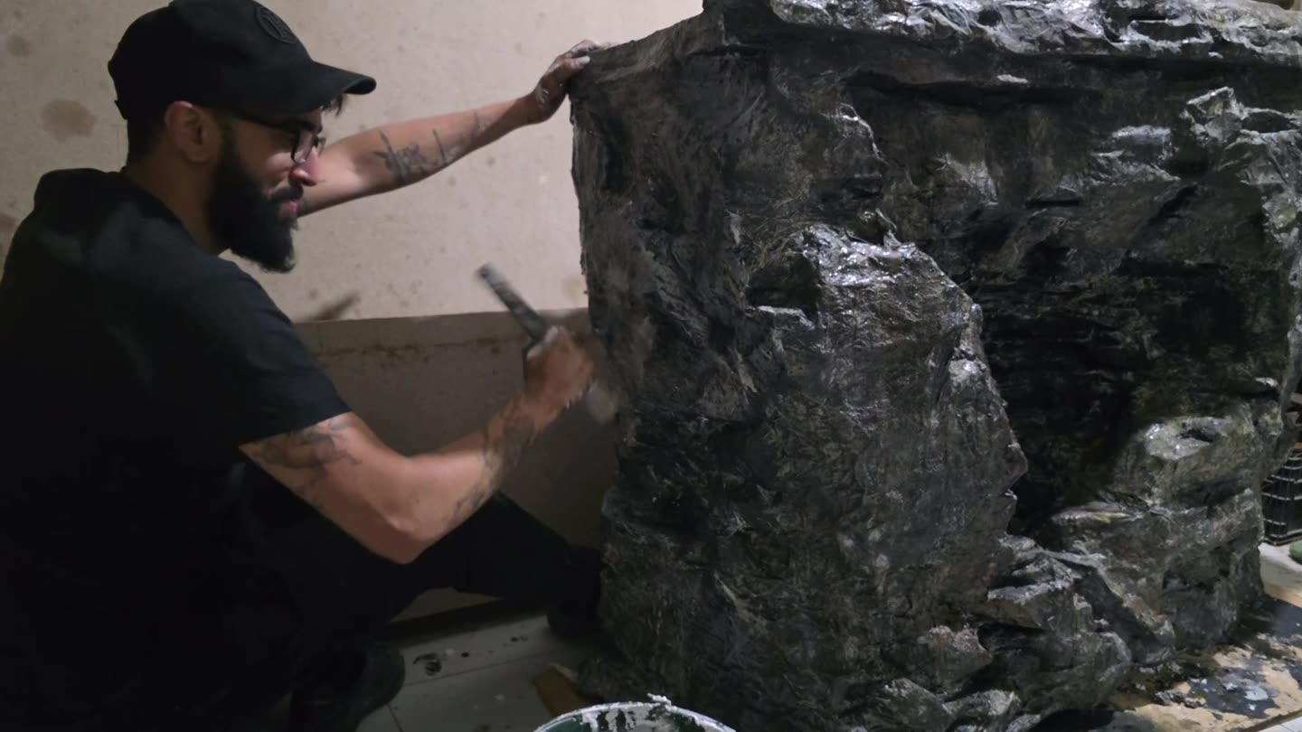 Construction de décor pour un clip au Maroc : un décorateur patine à la main un faux rocher en résine dans un atelier