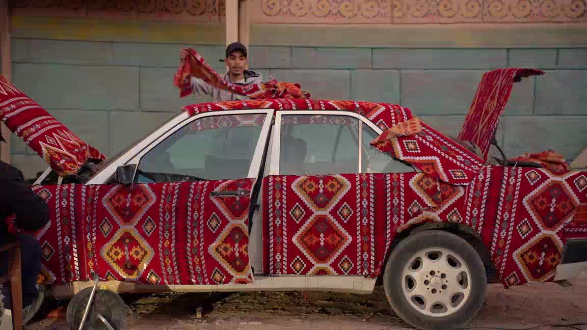 Décor construit pour un tournage au Maroc : accessoiriste habillant une voiture de tapis marocains