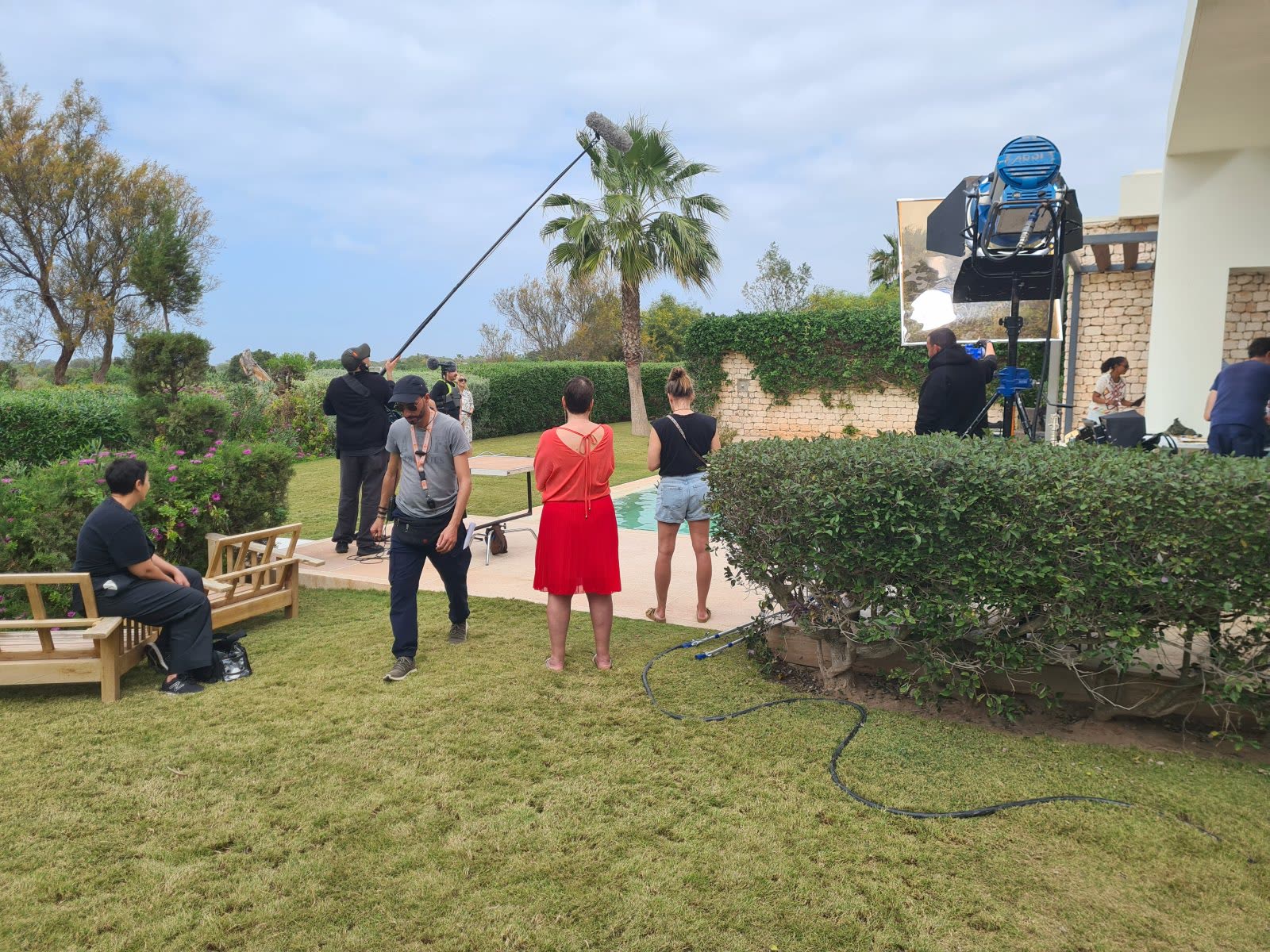 Tournage de publicité au Maroc : équipe technique, perche son et projecteur HMI installés dans le jardin d'une villa